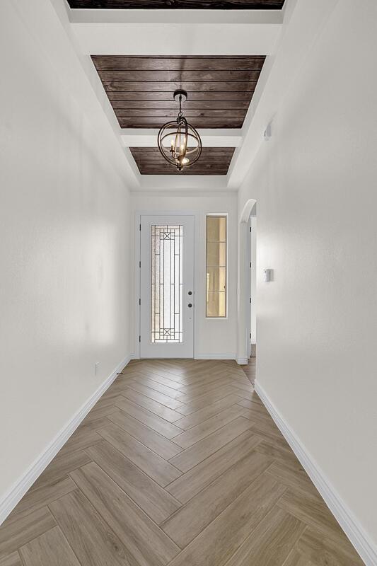 entrance foyer featuring wooden ceiling, light parquet flooring, a raised ceiling, and an inviting chandelier