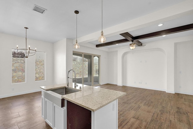 kitchen featuring sink, hardwood / wood-style flooring, light stone countertops, and pendant lighting