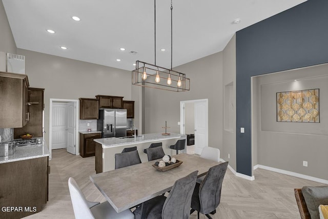 dining room with a high ceiling, sink, and light parquet floors