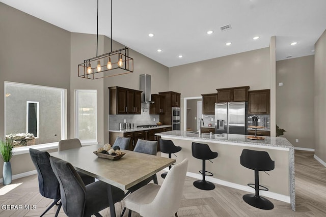 dining room with sink, a high ceiling, and light wood-type flooring