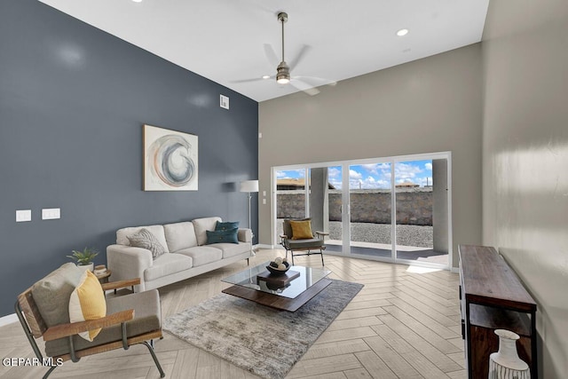 living room with ceiling fan, a towering ceiling, and light parquet floors