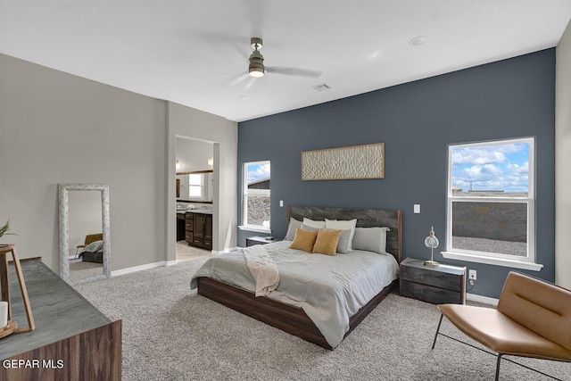 bedroom featuring light carpet, ceiling fan, and ensuite bath
