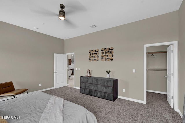 bedroom with ceiling fan, carpet flooring, and a walk in closet