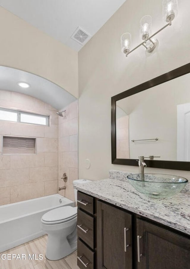 full bathroom with toilet, vanity, tiled shower / bath, and wood-type flooring