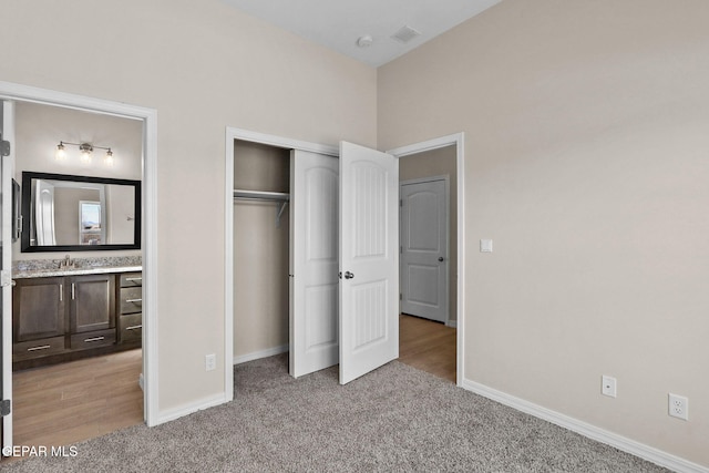 unfurnished bedroom with sink, a closet, light colored carpet, and ensuite bath