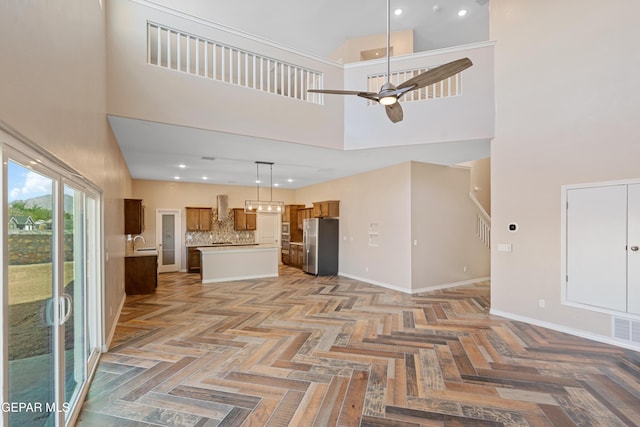 unfurnished living room featuring ceiling fan, light parquet floors, and a towering ceiling