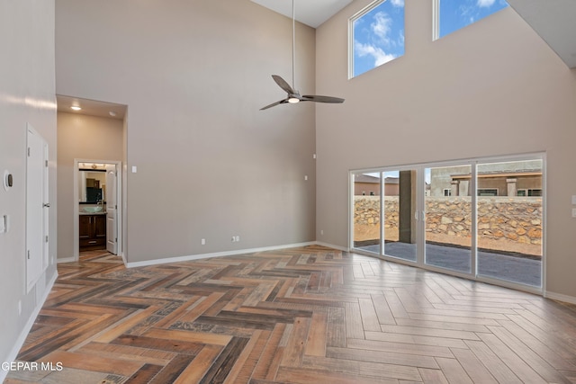 unfurnished living room featuring a high ceiling, dark parquet flooring, and ceiling fan