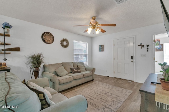 living room featuring a textured ceiling, ceiling fan, and light hardwood / wood-style flooring