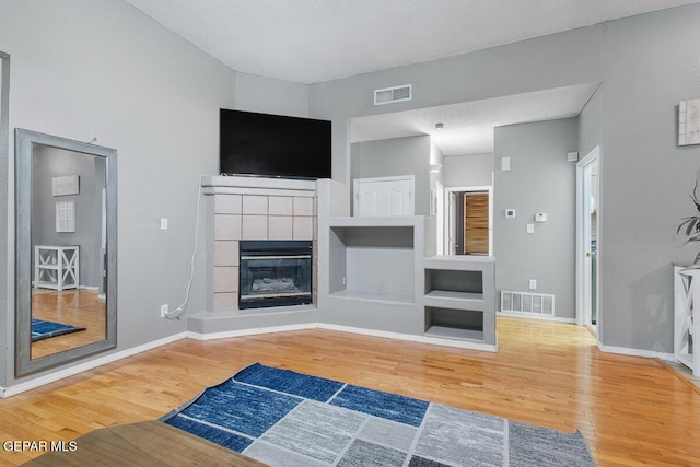 unfurnished living room featuring a tile fireplace and hardwood / wood-style floors