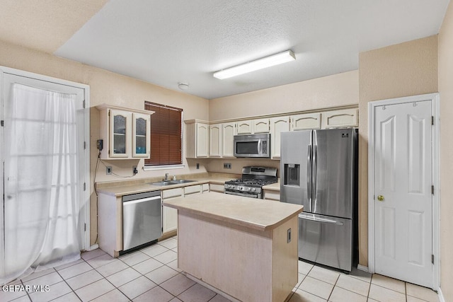 kitchen with a kitchen island, sink, light tile patterned floors, a textured ceiling, and appliances with stainless steel finishes