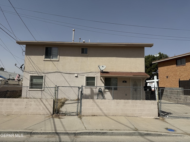 view of front of house featuring a fenced front yard, a gate, and stucco siding