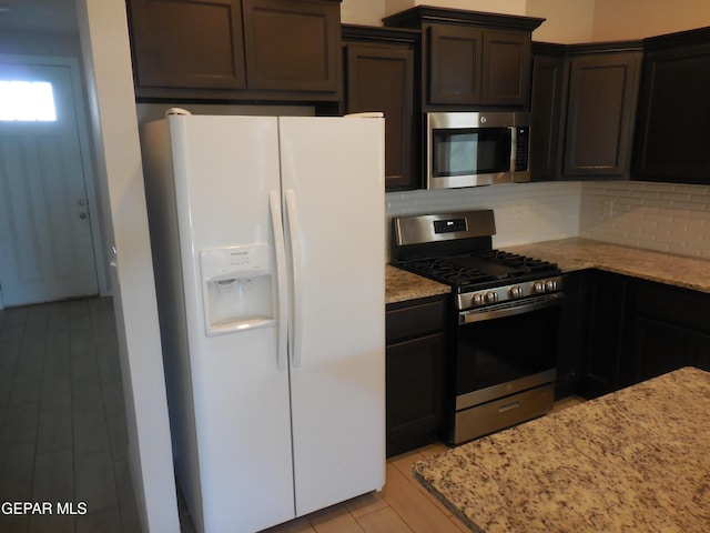 kitchen with backsplash, stainless steel appliances, light stone counters, and dark brown cabinetry