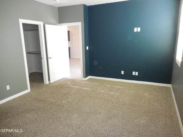 unfurnished bedroom featuring carpet floors, a closet, and a walk in closet