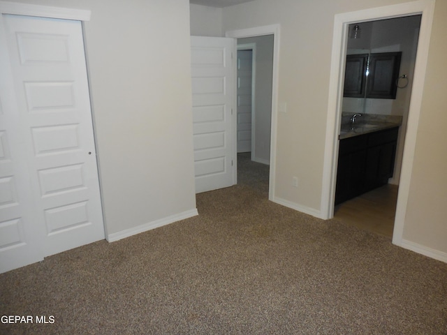 unfurnished bedroom with sink, carpet flooring, ensuite bath, and a closet