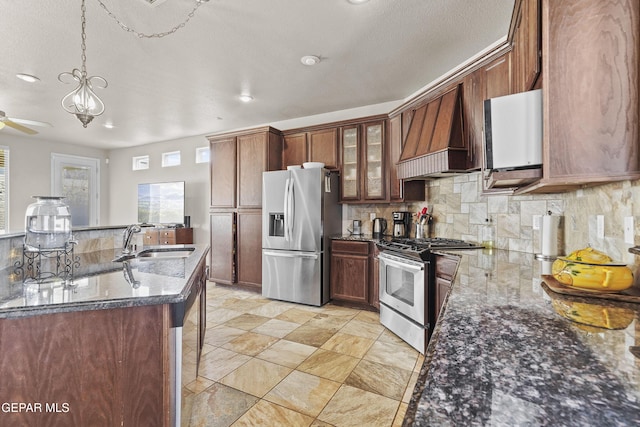 kitchen featuring a sink, custom range hood, appliances with stainless steel finishes, glass insert cabinets, and pendant lighting