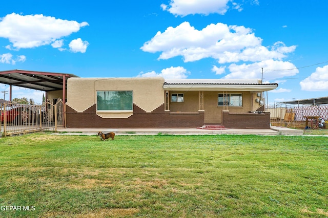 rear view of house featuring a lawn and a carport