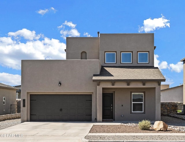 pueblo-style home with an attached garage, roof with shingles, concrete driveway, and stucco siding