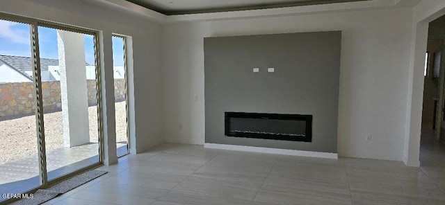 unfurnished living room featuring a glass covered fireplace and light tile patterned floors