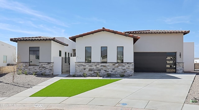 mediterranean / spanish house with a tile roof, stucco siding, an attached garage, stone siding, and driveway