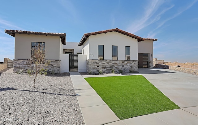 view of front facade featuring a garage, stone siding, a front lawn, and concrete driveway