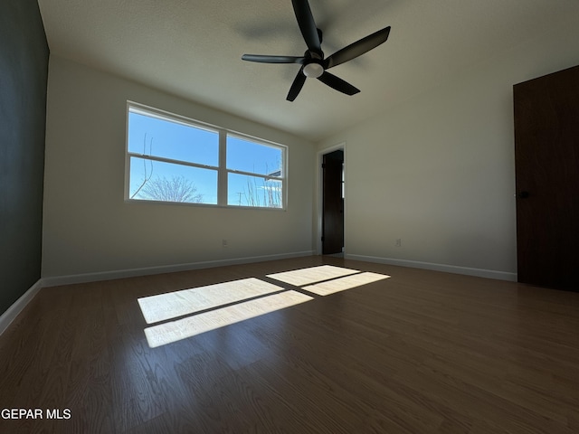 unfurnished room featuring a ceiling fan, dark wood finished floors, and baseboards