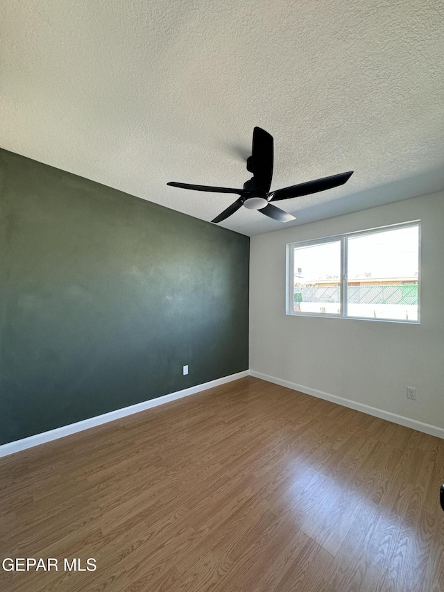 spare room featuring a ceiling fan, a textured ceiling, baseboards, and wood finished floors