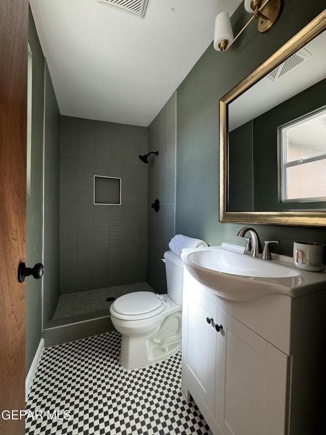 bathroom featuring toilet, a stall shower, visible vents, and vanity