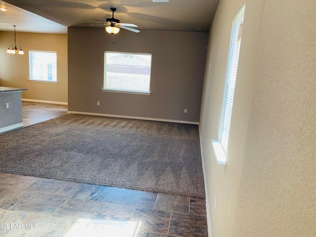 carpeted empty room featuring ceiling fan with notable chandelier