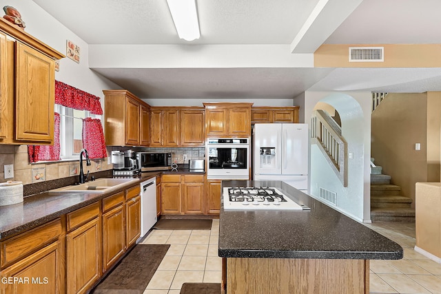 kitchen featuring appliances with stainless steel finishes, dark countertops, a kitchen island, and visible vents