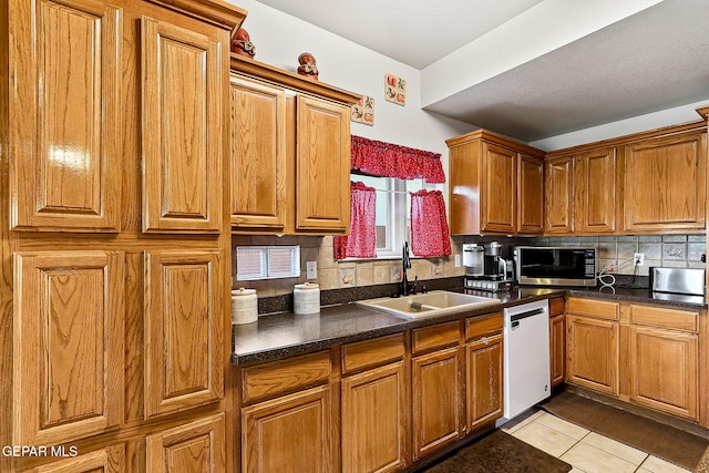 kitchen with light tile patterned floors, a sink, dishwasher, stainless steel microwave, and dark countertops