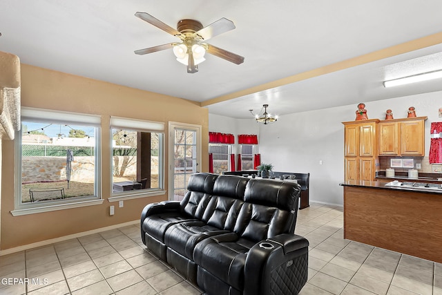 living area featuring light tile patterned floors, baseboards, and ceiling fan with notable chandelier