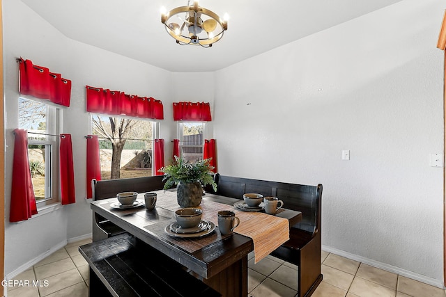 dining space with an inviting chandelier, light tile patterned floors, and baseboards