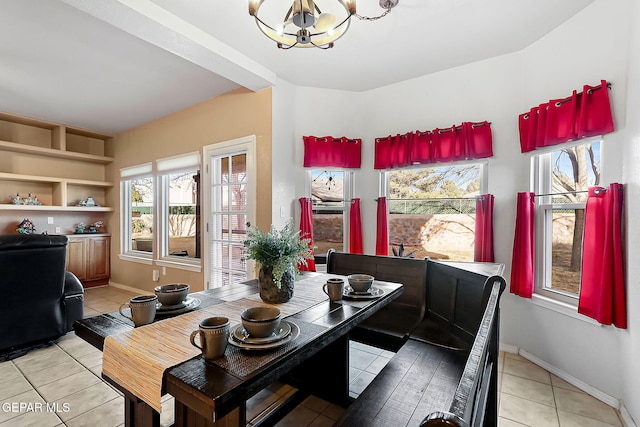 dining room with light tile patterned flooring, baseboards, and an inviting chandelier