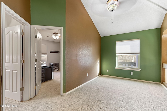 carpeted empty room with baseboards, vaulted ceiling, and a ceiling fan