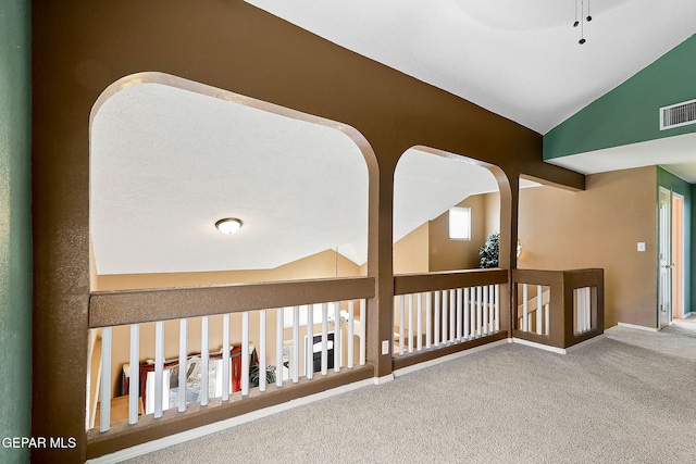 hallway featuring lofted ceiling, baseboards, visible vents, and carpet flooring