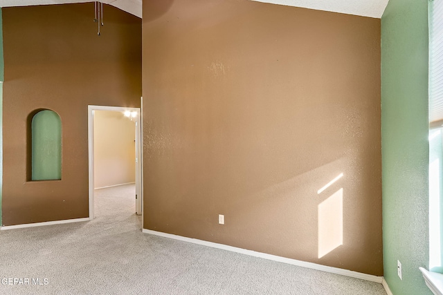 spare room with baseboards and light colored carpet