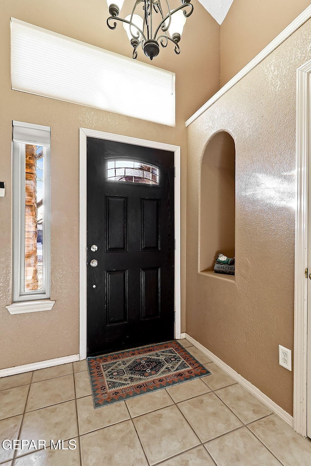 foyer with light tile patterned floors, baseboards, and a notable chandelier