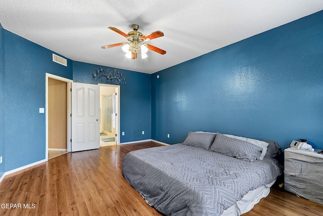 bedroom with baseboards, visible vents, and wood finished floors