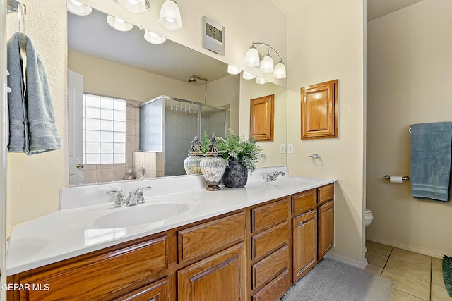 bathroom featuring double vanity, a sink, toilet, and tile patterned floors