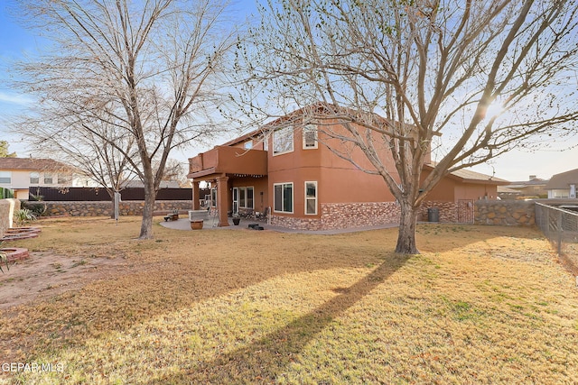 rear view of house featuring a yard, a patio area, a fenced backyard, and stucco siding