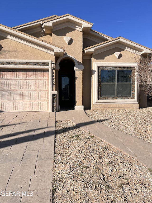 view of front of home with driveway, an attached garage, and stucco siding