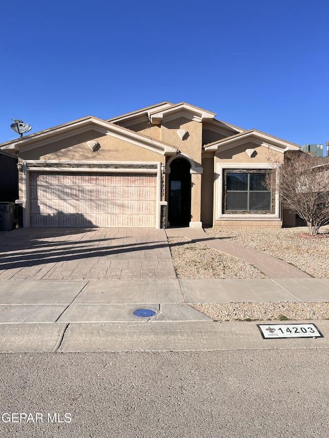 ranch-style house with driveway, an attached garage, and stucco siding