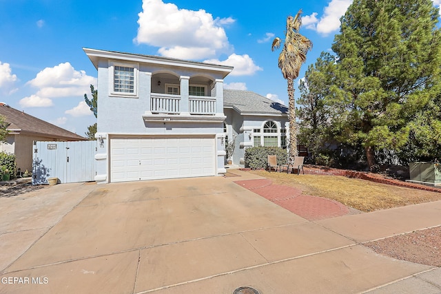 traditional-style home featuring stucco siding, concrete driveway, a gate, a balcony, and a garage