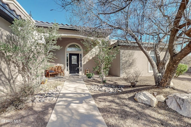 view of exterior entry featuring a tiled roof and stucco siding