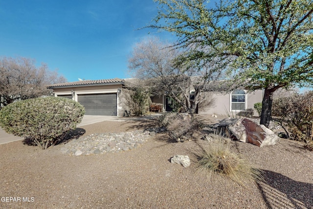 view of front facade with a garage, driveway, a tiled roof, and stucco siding