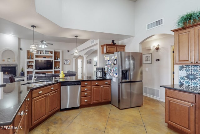 kitchen featuring arched walkways, brown cabinets, stainless steel appliances, visible vents, and open floor plan