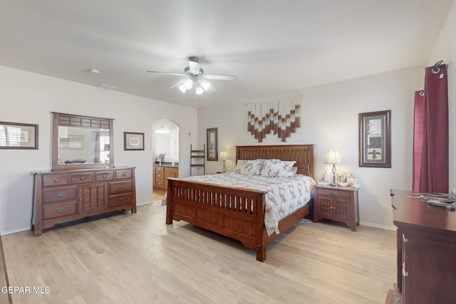 bedroom featuring arched walkways, ceiling fan, light wood-style flooring, and baseboards