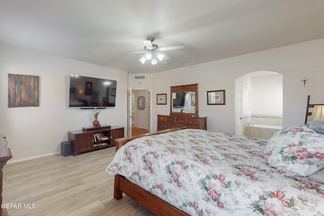 bedroom with arched walkways, connected bathroom, visible vents, and light wood-style floors