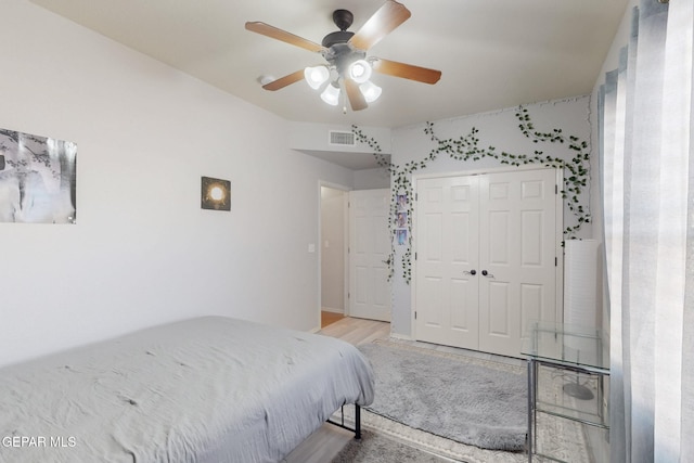 bedroom featuring light wood-style floors, a closet, visible vents, and ceiling fan