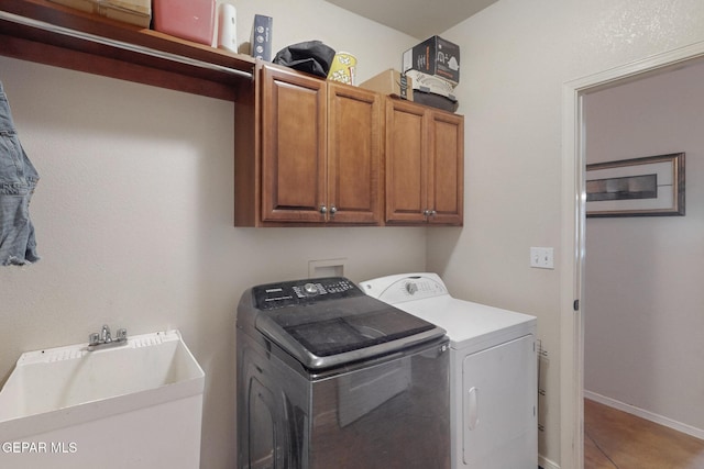 clothes washing area with cabinet space, baseboards, washer and clothes dryer, tile patterned floors, and a sink